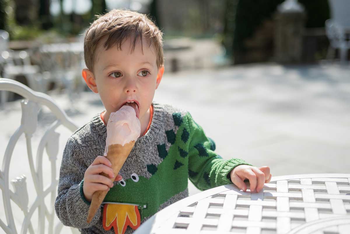 Young boy eating an ice cream whilst sat outside