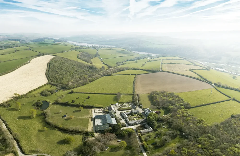 Aerial view of Tredethick Farm Cottages surrounded by fields and woodland.