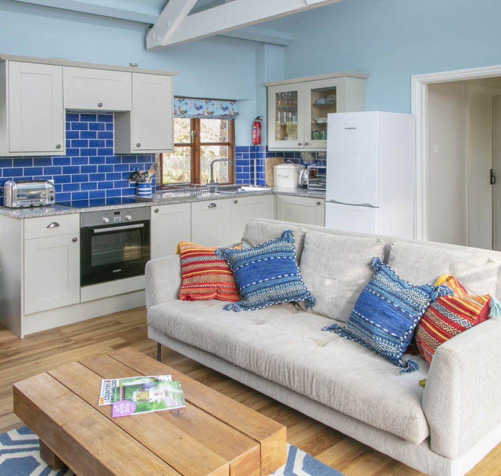 Kitchen and living area with modern anemities and coffee table. This holiday cottage in Cornwall is decorated so that it is perfect for baby friendly holidays.