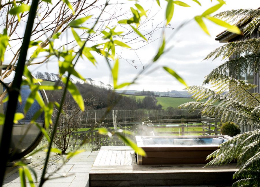 Landscape shot of the hot tub and garden pod through the trees at Tredethick
