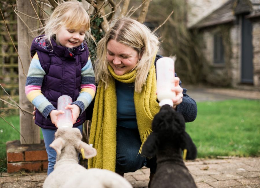 Woman and young girl bottle feeding a baby lamb at Tredethick