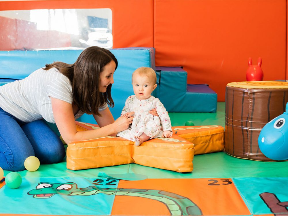 Mum and baby in a brightly coloured soft play space together