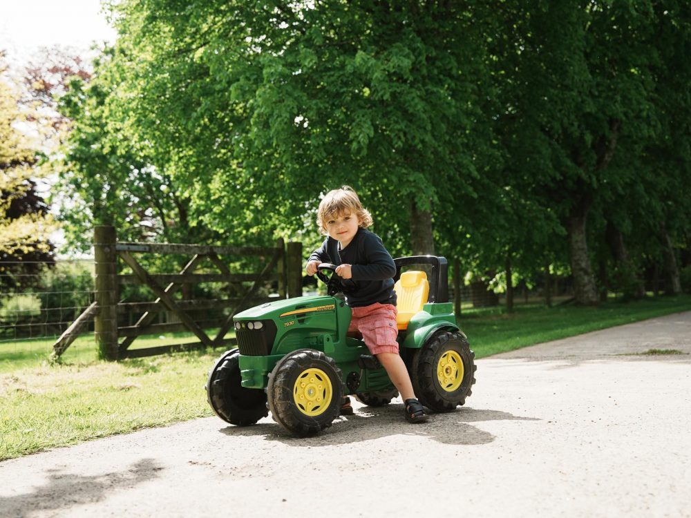 A young boy sitting on a mini tractor at Tredethick