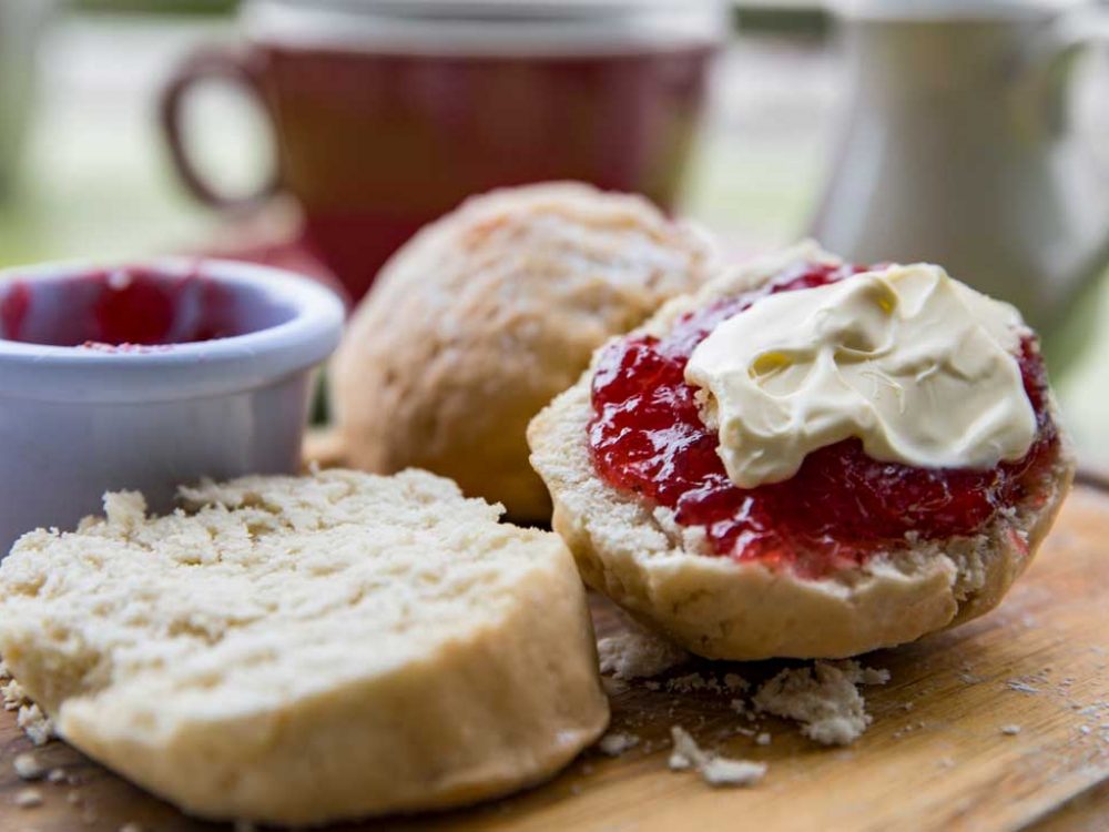 Close up of a scone with jam and cream on it