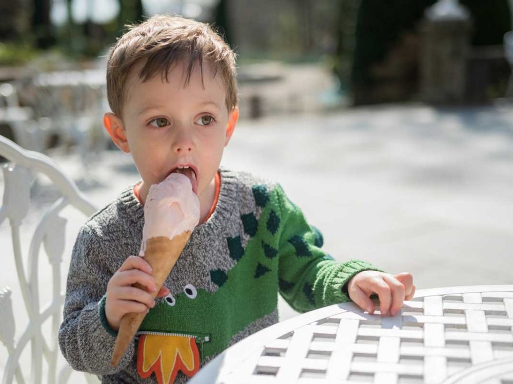 Young boy eating an ice cream whilst sat outside